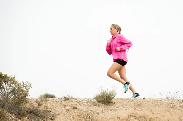 Junge Sportlerin läuft abseits der Straße Trail schmutzige Straße mit trockener Wüstenlandschaft Hintergrundtraining hart — Stockfoto