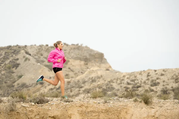 Joven deporte mujer corriendo fuera de camino camino camino sucio con seco desierto paisaje fondo entrenamiento duro — Foto de Stock