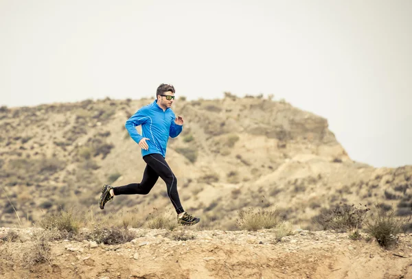 Sportler läuft auf Offroad-Trail schmutzige Straße mit trockener Wüstenlandschaft Hintergrundtraining hart — Stockfoto