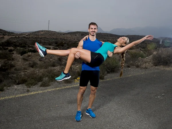 Young sport couple happy together outdoors on mountain landscape man holding girl on his strong arms having fun — ストック写真