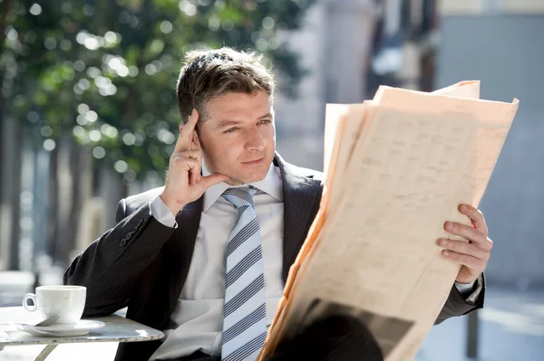Atractivo hombre de negocios sentado al aire libre tomando café leyendo noticias de periódico relajado —  Fotos de Stock