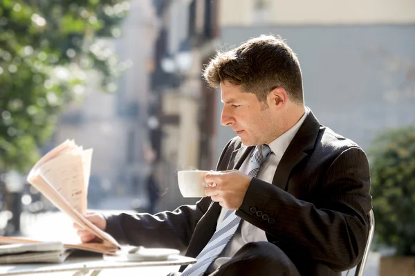 Zakenman zitten buiten voor ontbijt pauze ochtend lezen van nieuws in de krant met koffie — Stockfoto