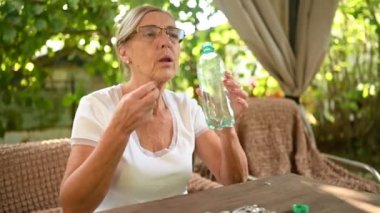 Gözlüklü yaşlı kadın bahçede vitamin hapları alıyor. Sağlık Hizmetleri Yaşlıları Konsepti