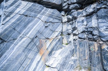Kaya, doğal ortamda beyaz ve gri mermerin ham yüzeyini kesti. Mavi mermer kariyer dokusu. Gerçek taş, binalar ve iç kısımlar için endüstriyel malzeme. Soyut arkaplan deseni