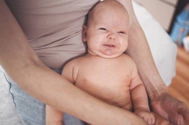 Sevimli, duygusal, komik, gülümseyen, yeni doğmuş bir bebek, annesinin ellerinde oturuyor. Bebek eşyaları paketleme şablonu. Sağlıklı çocuk, hastane kavramı ve mutlu annelik. Bebek, bebek. Çocuk odası..