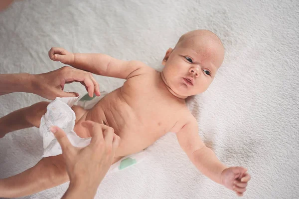 妈妈正在换尿布可爱的情绪古怪的新生儿宝宝躺在婴儿床里 婴儿用品包装模板 健康的孩子 医院的概念和快乐的母性 幼儿园 — 图库照片