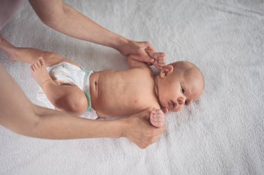 Annem bebek beziyle bebek için egzersiz yapıyor. Beşikteki sevimli, duygusal, komik, yeni doğmuş çocuk. Bebek eşyaları paketleme şablonu. Sağlıklı çocuk, hastane kavramı ve mutlu annelik. Bebek, bebek. Çocuk odası..