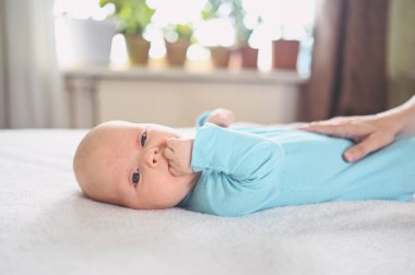 Mavi tulumlu ağlayan tatlı duygusal yeni doğmuş çocuk yatakta yatıyor. Bebek yüz ifadeleri. Bebek eşyaları paketleme şablonu. Sağlıklı çocuk, hastane kavramı ve mutlu annelik. Bebek, bebek. Çocuk odası..