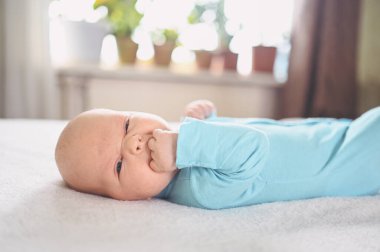 Mavi tulumlu ağlayan tatlı duygusal yeni doğmuş çocuk yatakta yatıyor. Bebek yüz ifadeleri. Bebek eşyaları paketleme şablonu. Sağlıklı çocuk, hastane kavramı ve mutlu annelik. Bebek, bebek. Çocuk odası..