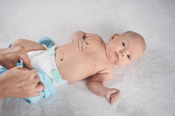 妈妈穿着一件蓝色的连衣裙 穿着可爱的 感情上有趣的新生男婴 婴儿用品包装模板 穿着尿布的健康孩子 医院的概念和快乐的母亲 幼儿园 — 图库照片