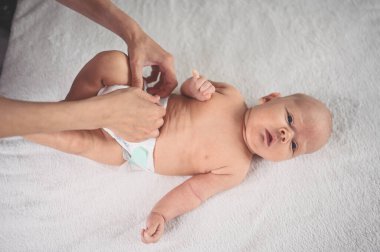 Annem bebek bezi değiştiriyor. Sevimli, duygusal, komik, yeni doğmuş bebek bebek beşikte yatıyor. Bebek eşyaları paketleme şablonu. Sağlıklı çocuk, hastane kavramı ve mutlu annelik. Bebek, bebek. Çocuk odası..