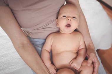 Sevimli, duygusal, komik, gülümseyen, yeni doğmuş bir bebek, annesinin ellerinde oturuyor. Bebek eşyaları paketleme şablonu. Sağlıklı çocuk, hastane kavramı ve mutlu annelik. Bebek, bebek. Çocuk odası..