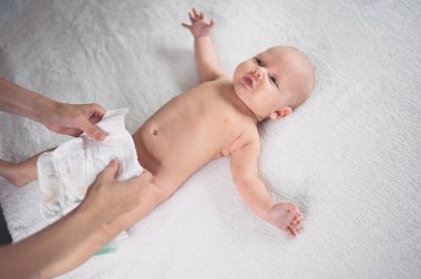 Annem bebek bezi değiştiriyor. Sevimli, duygusal, komik, yeni doğmuş bebek bebek beşikte yatıyor. Bebek eşyaları paketleme şablonu. Sağlıklı çocuk, hastane kavramı ve mutlu annelik. Bebek, bebek. Çocuk odası..