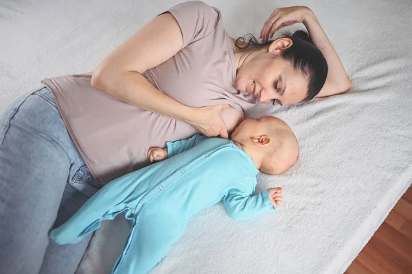 Mladá Matka Leží Novorozeně Roztomilé Dítě Modré Kombinéze Posteli Objímání — Stock fotografie