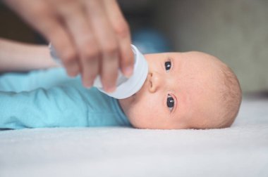 Süt şişesiyle yatakta yatan sevimli, duygusal, komik, yeni doğmuş çocuk. Bebek yüz ifadeleri. Bebek eşyaları paketleme şablonu. Sağlıklı çocuk, hastane kavramı ve mutlu annelik. Bebek, bebek. Çocuk odası..