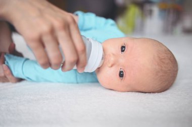 Süt şişesiyle yatakta yatan sevimli, duygusal, komik, yeni doğmuş çocuk. Bebek yüz ifadeleri. Bebek eşyaları paketleme şablonu. Sağlıklı çocuk, hastane kavramı ve mutlu annelik. Bebek, bebek. Çocuk odası..