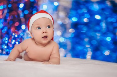 Bebeğin ilk Noel 'i. Noel Baba şapkalı çocuk. Sevimli duygusal gülümseme komik yeni doğan yüz ifadeleri.