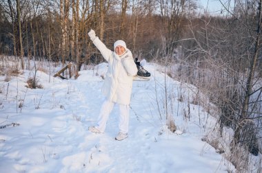 Beyaz, sıcak, güneşli kış aylarında buz patenleriyle oynayan yaşlı, mutlu, olgun bir kadın. Emekli sağlıklı insanlar tatil, kış aktiviteleri, aktif yaşam tarzı konsepti