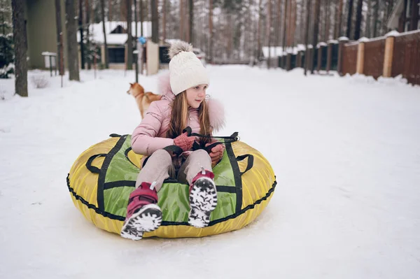 在外面雪白寒冷的冬天 穿着粉色保暖外套的可爱小女孩在外面玩乐地坐着充气雪管 家庭体育休假日活动 — 图库照片