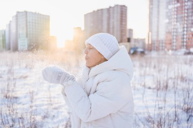 Beyaz, sıcak, güneşli kışın açık havada karla oynayan yaşlı, mutlu, olgun bir kadın. Emekli sağlıklı insanlar tatil, kış aktiviteleri, aktif yaşam tarzı konsepti