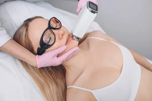 Yaşlanma karşıtı prosedürler. Deri bakımı konsepti. Kadın güzellik tedavisi görüyor, kozmetik kliniğindeki pigmentasyonu kaldırıyor. Yoğun titreşimli ışık terapisi. IPL. Yenilenme, fotoğraf yüz terapisi..