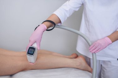 Güzellik salonunda lazer epilasyonu ve kozmetoloji. Saç çıkarma prosedürü. Lazer epilasyonu, kozmetoloji, spa ve saç temizleme konsepti. Güzel sarışın kadın saçlarını bacaklarından ayırıyor.