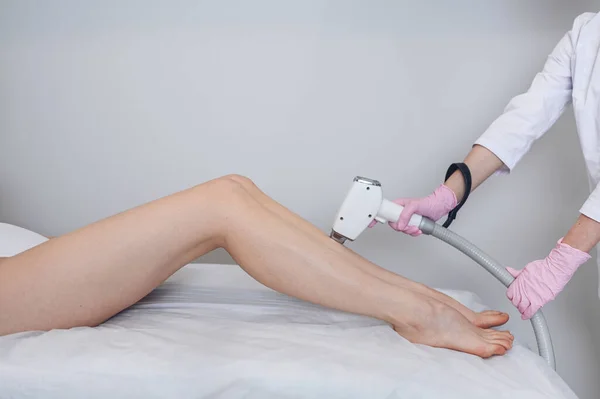 Laser epilation and cosmetology in beauty salon. Hair removal procedure. Laser epilation, cosmetology, spa, and hair removal concept. Beautiful blonde woman getting hair removing on legs