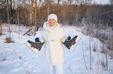 Beyaz, sıcak, güneşli kış aylarında buz patenleriyle oynayan yaşlı, mutlu, olgun bir kadın. Emekli sağlıklı insanlar tatil, kış aktiviteleri, aktif yaşam tarzı konsepti