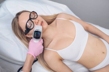 Yaşlanma karşıtı prosedürler. Deri bakımı konsepti. Kadın güzellik tedavisi görüyor, kozmetik kliniğindeki pigmentasyonu kaldırıyor. Yoğun titreşimli ışık terapisi. IPL. Yenilenme, fotoğraf yüz terapisi..