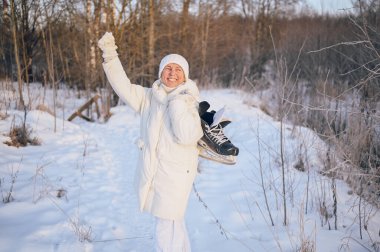 Beyaz, sıcak, güneşli kış aylarında buz patenleriyle oynayan yaşlı, mutlu, olgun bir kadın. Emekli sağlıklı insanlar tatil, kış aktiviteleri, aktif yaşam tarzı konsepti