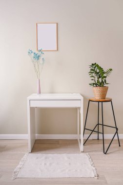 Minimalist kadın hala iş yerinde iç pastel renkler. Beyaz masa, boş poster çerçeve, mavi kuru çiçekli pembe vazo. Eko hasır saksıda ev bitkisi. Şablon