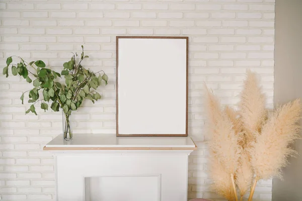 Beyaz sahte şöminesi, boş resim çerçevesi, kurutulmuş çiçekleri, otları olan oturma odasının zarif eko kompozisyonu. Modern ev dekorasyonu. Şablon. Duvardaki poster çerçevesini düzenle.