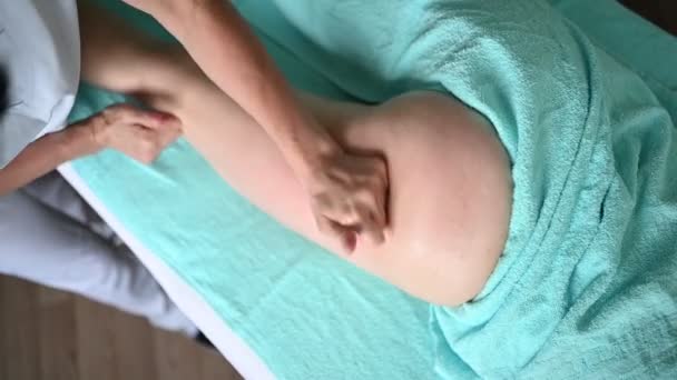 Junge unkenntliche Frau liegt auf Massagetisch und genießt therapeutische Hüftmassage. Körperpflege, Abnehmkonzept. Handmasseur Massagetherapeut tut Anti-Cellulite-Massage in Kurklinik. — Stockvideo