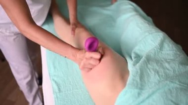 Masaj masasında uzanmış, vakum kavanozlarını rahatlatan, terapi masajı yapan tanınmamış bir kadın. Vücut bakımı, kilo verme konsepti. El masajı terapisti spa kliniğinde anti-selülit masaj yapıyor..