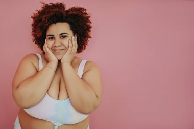 Mutlu, gülümseyen, aşırı büyük, siyah Afrikalı kadın saçı, mayo içinde poz veriyor, pembe arka plan izole edilmiş, vücut kusuru, vücut kabulü, vücut pozitifliği ve çeşitlilik kavramı. Boşluğu kopyala.