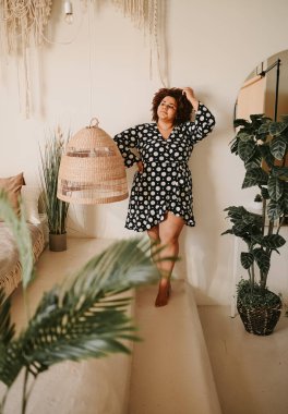 Kıvrımlı, Afrikalı, siyah, siyah, siyah, siyah saçlı, siyah saçlı, ev bitkileriyle çevrili, çevre dostu, samimi yatak odası iç tasarımı. Vücut kusuru, beden kabulü, vücut pozitifliği ve çeşitlilik kavramı