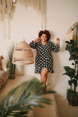 Kıvrımlı, Afrikalı, siyah, siyah, siyah, siyah saçlı, siyah saçlı, ev bitkileriyle çevrili, çevre dostu, samimi yatak odası iç tasarımı. Vücut kusuru, beden kabulü, vücut pozitifliği ve çeşitlilik kavramı