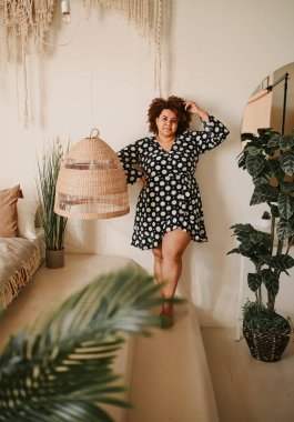 Kıvrımlı, Afrikalı, siyah, siyah, siyah, siyah saçlı, siyah saçlı, ev bitkileriyle çevrili, çevre dostu, samimi yatak odası iç tasarımı. Vücut kusuru, beden kabulü, vücut pozitifliği ve çeşitlilik kavramı