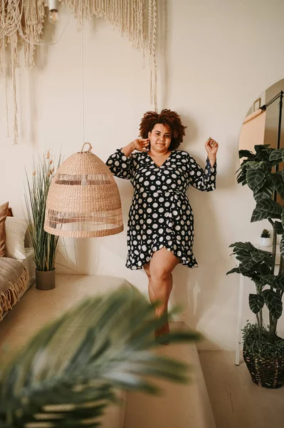 Kıvrımlı, Afrikalı, siyah, siyah, siyah, siyah saçlı, siyah saçlı, ev bitkileriyle çevrili, çevre dostu, samimi yatak odası iç tasarımı. Vücut kusuru, beden kabulü, vücut pozitifliği ve çeşitlilik kavramı