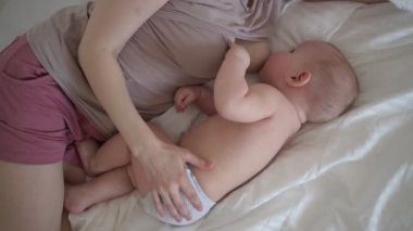 Genç anne, yeni doğmuş tatlı bir bebekle yatakta yatıyor. Çıplak erkek çocuğu kollarına alıyor, anne sütüyle sarılıp emziriyor. Sağlıklı çocuk, hastane kavramı ve mutlu annelik. Çocuk odası.