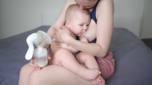 Молодая мать с новорожденным милым обнаженным младенцем, держа его на руках, обнимая грудным насосом и кормясь грудным молоком. Здоровый ребенок, концепция больницы и счастливое материнство. Детская комната. — стоковое видео