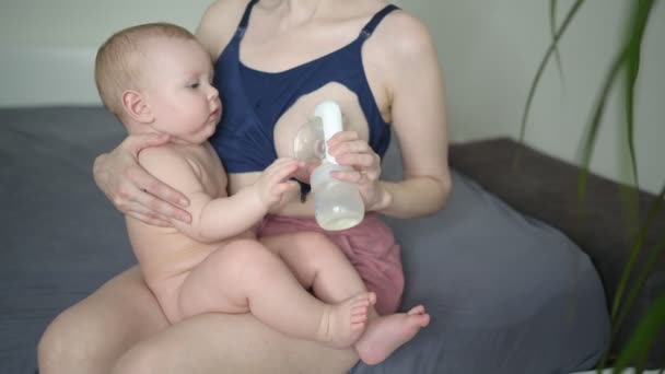 Jonge moeder met pasgeboren schattige baby naakte baby jongen, houdt hem op de armen, met behulp van borstpomp knuffelen en borstvoeding met moedermelk. Gezond kind, concept van ziekenhuis en gelukkig moederschap. Kwekerij. — Stockvideo