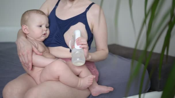 Jonge moeder met pasgeboren schattige baby naakte baby jongen, houdt hem op de armen, met behulp van borstpomp knuffelen en borstvoeding met moedermelk. Gezond kind, concept van ziekenhuis en gelukkig moederschap. Kwekerij. — Stockvideo