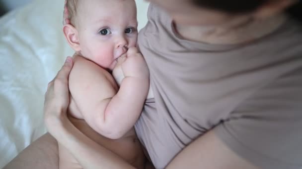 Молодая мать с новорожденным милым голым младенцем на кровати, держит его на руках, обнимает и кормит грудным молоком. Здоровый ребенок, концепция больницы и счастливое материнство. Детская комната — стоковое видео