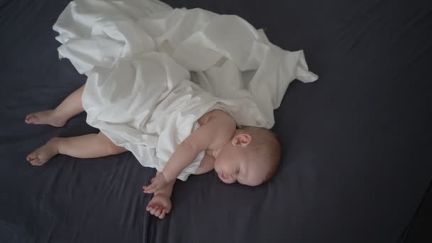 Симпатичный Новорожденный Ребенок Покрытый Белым Полотном Спит Серой Кровати — стоковое видео
