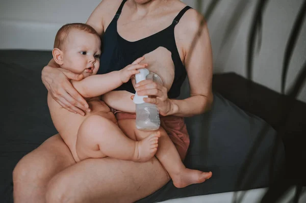 Ibu muda dengan bayi laki-laki lucu telanjang yang baru lahir, memeluknya di lengan, menggunakan pompa payudara memeluk dan menyusui dengan ASI. Anak yang sehat, konsep rumah sakit dan ibu yang bahagia. Anak-anak. — Stok Foto