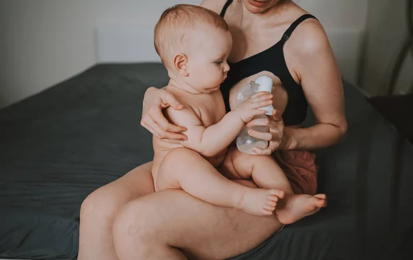 Młoda matka z noworodka cute niemowlę nagi chłopiec, trzymając go na ramionach, za pomocą pompy piersiowej przytulanie i karmi piersią z mlekiem matki. Zdrowe dziecko, koncepcja szpitala i szczęśliwe macierzyństwo. Przedszkole. — Zdjęcie stockowe