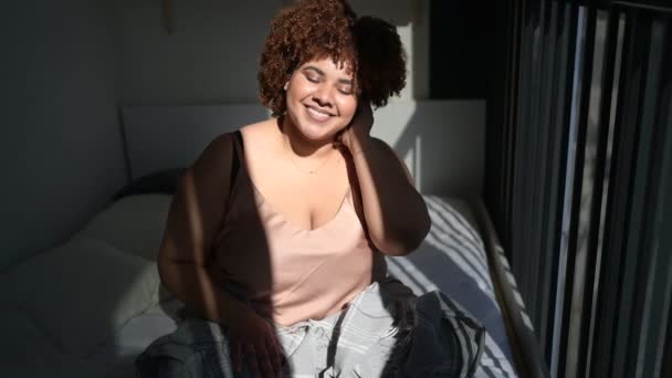 Hermoso curvas más tamaño africano negro mujer afro pelo en la cama con gris manta a cuadros acogedor dormitorio diseño interior. Luz solar. Imperfección corporal, aceptación corporal, concepto de cuerpo positivo y diversidad — Vídeos de Stock