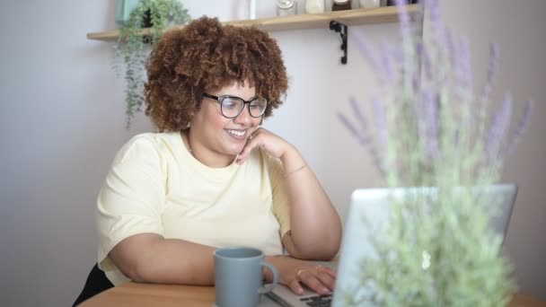 Attraktiv glad snygg plus storlek afrikansk svart kvinna student afro hår i glasögon studerar online arbetar på bärbar dator på hemmakontoret arbetsyta. Mångfald. Fjärrarbete, distansutbildning. — Stockvideo