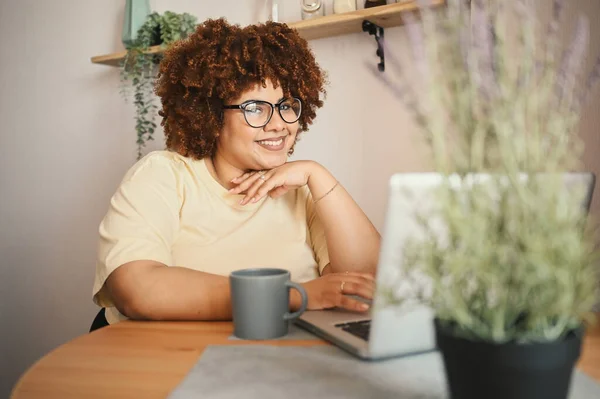 Attractive happy stylish plus size African black woman student afro hair in glasses studying online working on laptop computer at home office workspace. Diversity. Remote work, distance education. Royalty Free Stock Images